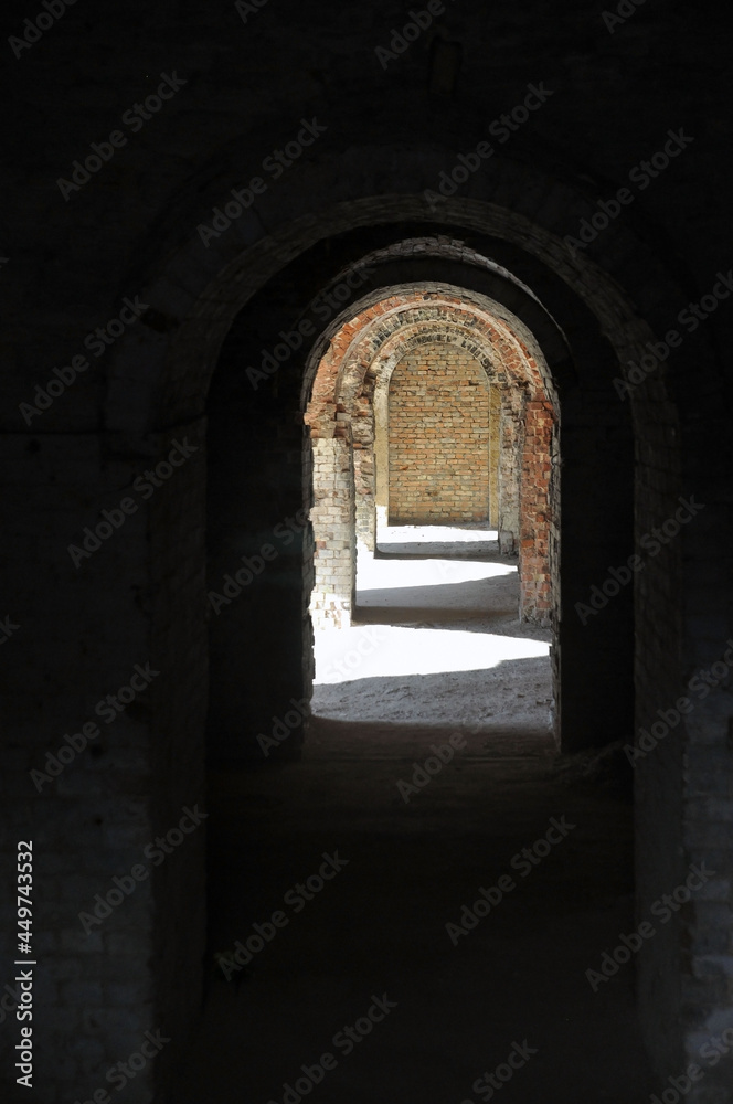A through corridor through the casemates of the defensive barracks in the rays of sunlight.