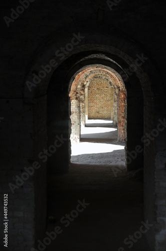 A through corridor through the casemates of the defensive barracks in the rays of sunlight.