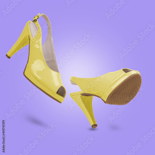 Trendy Yellow sandals with high heels in motion on a light purple background.