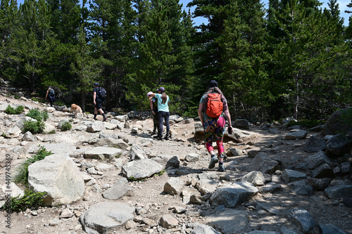 Hikers ascend Saint Mary's Glacier Trail in Arapaho National Forest, Colorado on sunny summer morning.