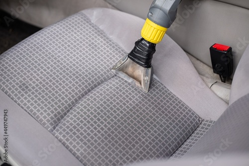 Obraz na płótnie Man car detailing studio worker cleaning car textile upholstery with vacuum washer w salonie