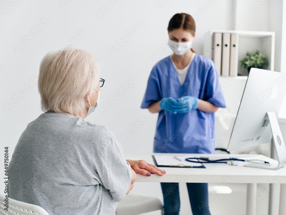 Obraz premium elderly woman patient sitting at the table in the doctor's office medical mask health immunization safety