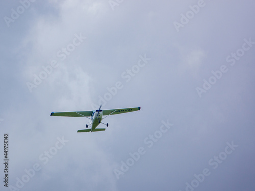 G-BNYM Cessna 172N Skyhawk (172-73854) a 4-seat, single engine, high wing light aircraft flying low overhead in a light cloud blue and white sky