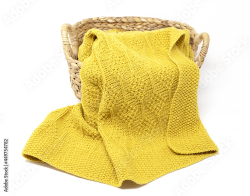 Yellow knitted blanket in diamonds pattern in basket on white background