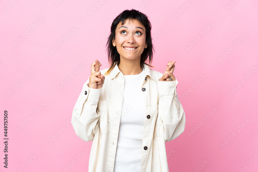 Young Uruguayan woman over isolated pink background with fingers crossing and wishing the best Young Uruguayan woman over isolated pink background with fingers crossing and wishing the best