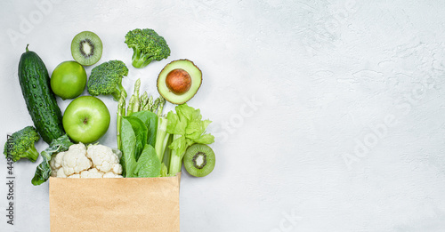 Fototapeta Naklejka Na Ścianę i Meble -  green vegetables and fruits in a paper bag on a light gray background