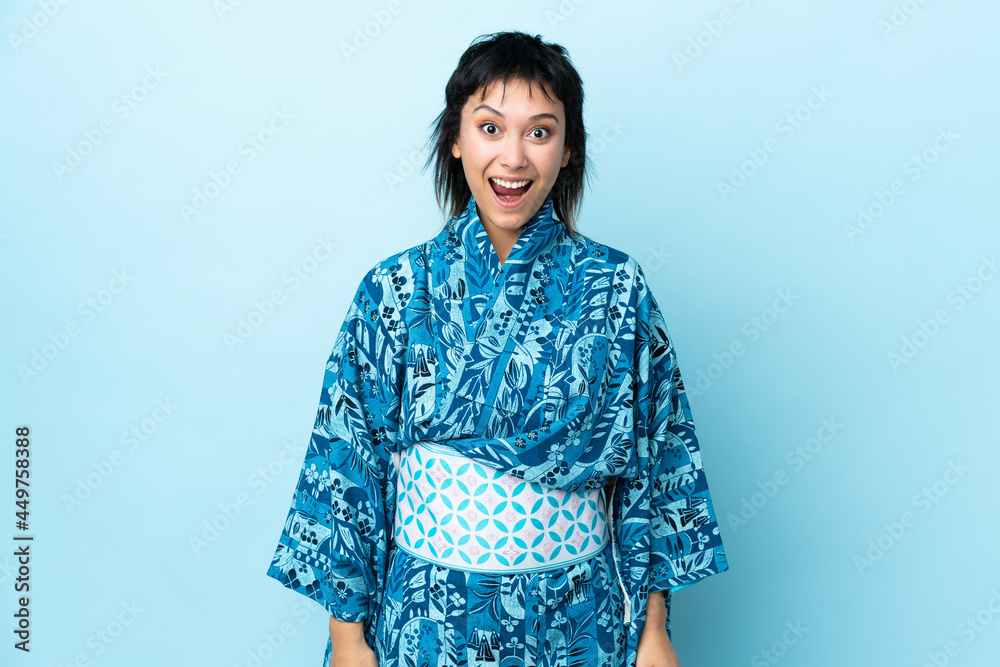 Fototapeta premium Young woman wearing kimono over isolated blue background with surprise facial expression