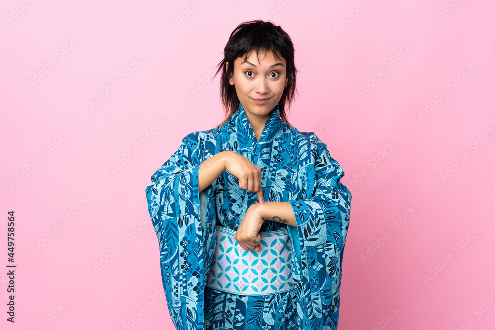 Young woman wearing kimono over isolated blue background making the gesture of being late Young woman wearing kimono over isolated blue background making the gesture of being late