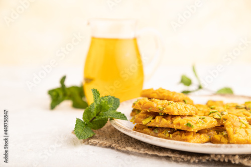 Traditional iranian dessert sohan with glass of green tea on a gray concrete background, side view, close up. photo