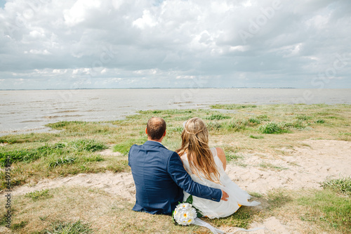 couple on the beach. Bride and groom sit next to each other on the beach. Couple in love sitting by the sea. Wedding for two on the beach 