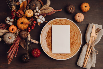 Rustic menu mockup with plate and autumn table decoration.  Floral interior decor for fall holidays with handmade pumpkins. Holiday dinner concept. Flatlay, top view.