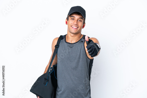 Young sport caucasian man with sport bag isolated on white background with thumbs up because something good has happened