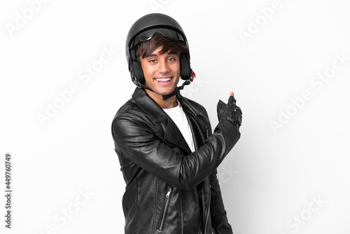 Young man with a motorcycle helmet isolated on white background pointing back