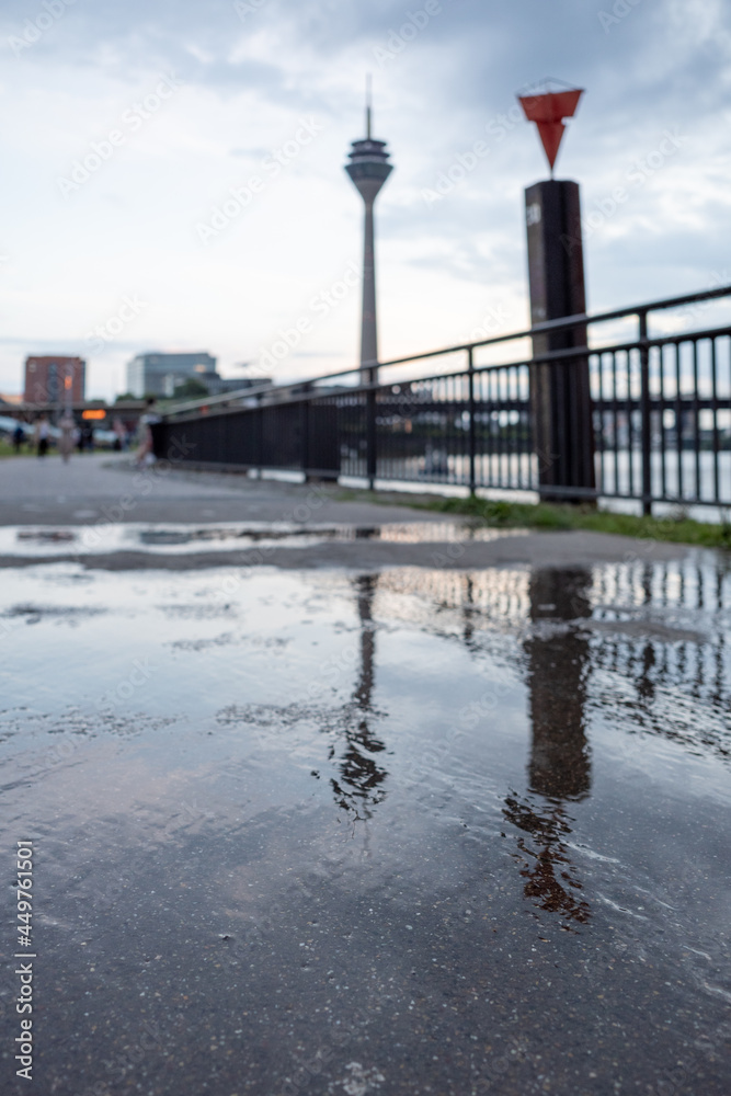 Low angle and selected focus view on reflection of Rhine tower on water after raining along promenade  riverside of Rhine River in Düsseldorf, Germany.