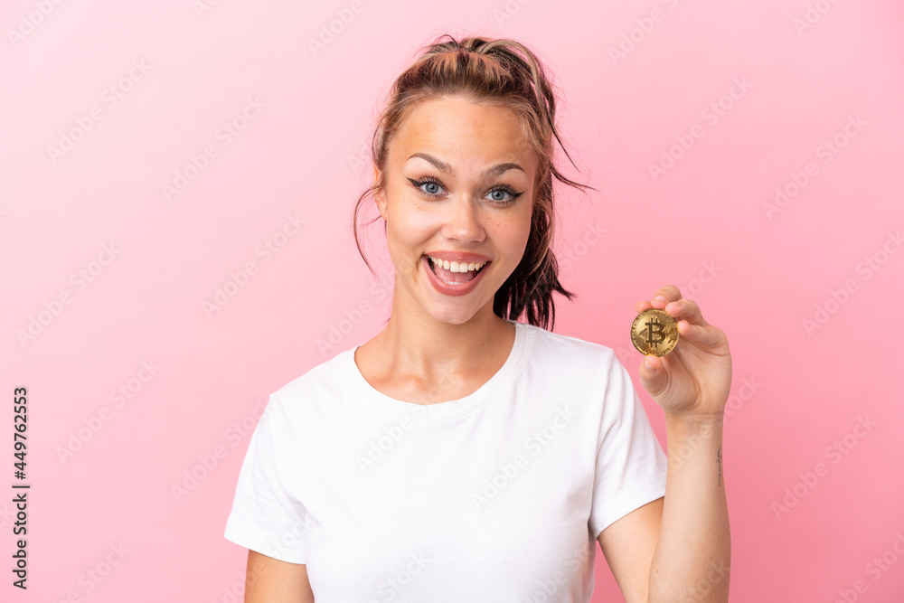 Teenager Russian girl holding a Bitcoin isolated on pink background with surprise facial expression Teenager Russian girl holding a Bitcoin isolated on pink background with surprise facial expression