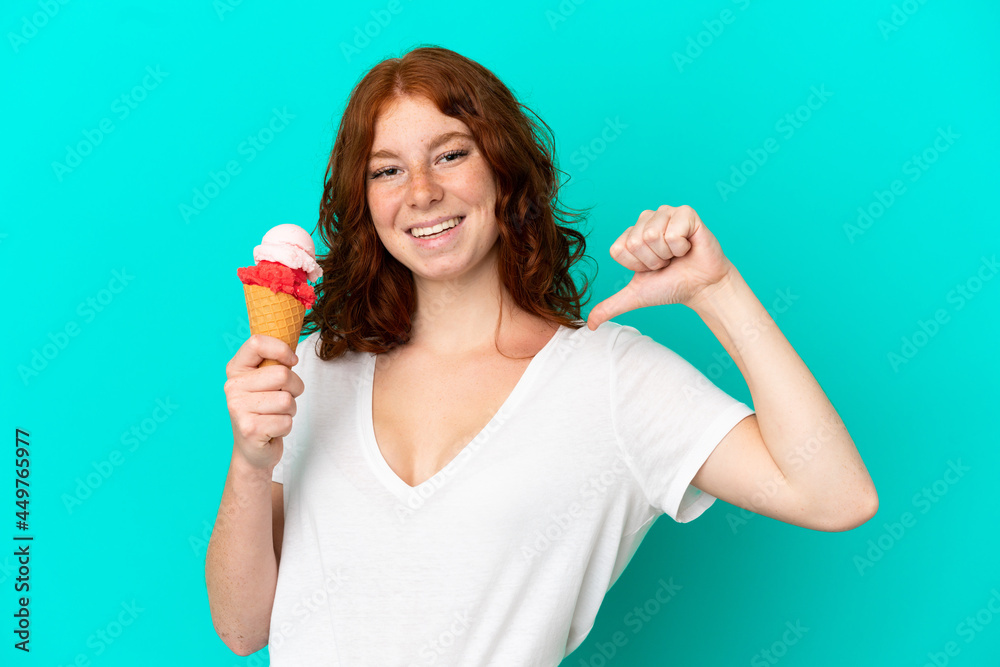 Teenager reddish woman with a cornet ice cream isolated on blue background proud and self-satisfied Teenager reddish woman with a cornet ice cream isolated on blue background proud and self-satisfied