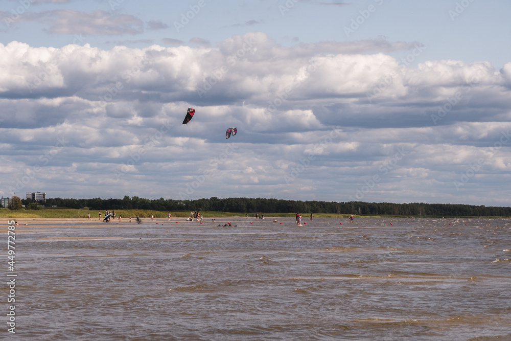 Parnu, Estonia / July 30, 2021: people practicing kyte-surfing on the beach in Parnu in the summer, beautiful colorful estonian city by the Baltic sea, Europe