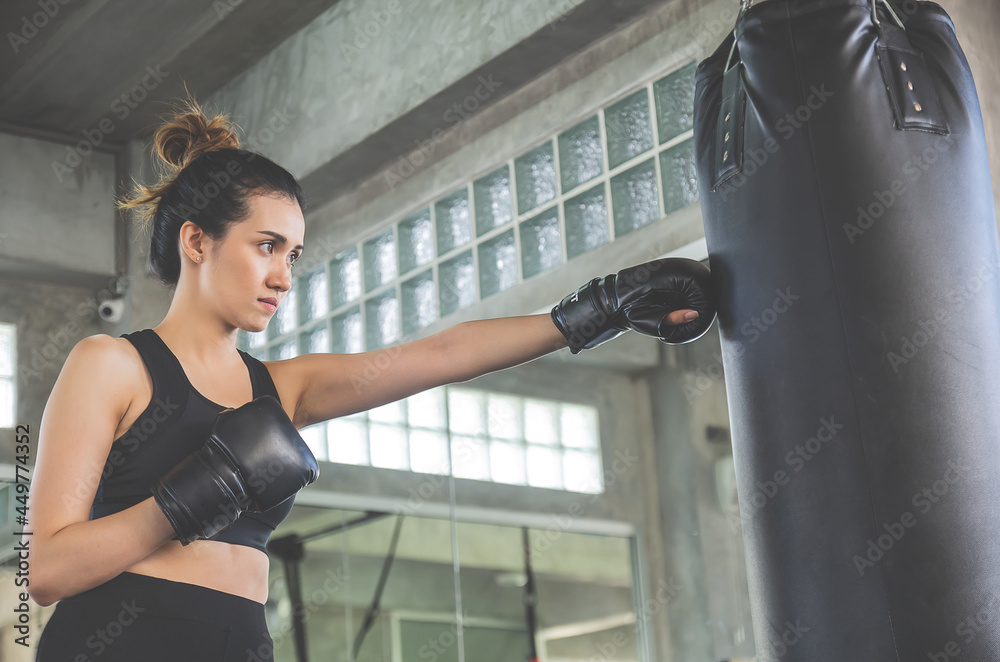 Beautiful asian woman wears boxing gloves knock sandbag in gym or sport center