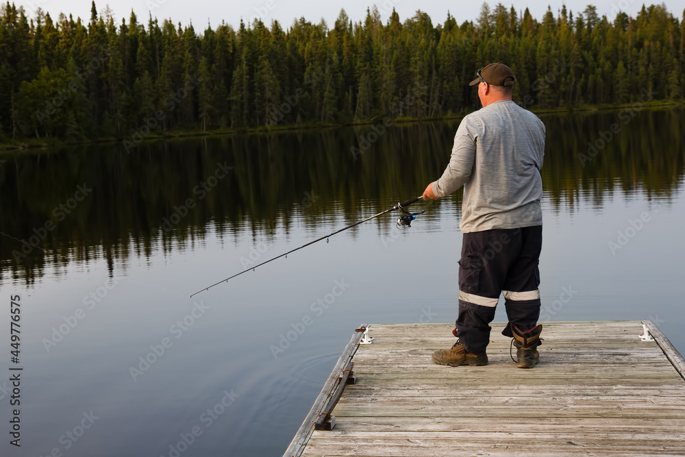 dock in lake water near forest with fisherman fishing with rod in summer