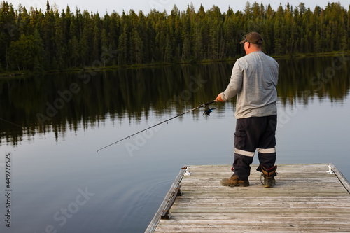 dock in lake water near forest with fisherman fishing with rod in summer