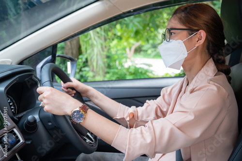 Young Asian woman wearing surgical mask while driving car. During covid-19 pandemic be sure to bring a mask with you when you leave home.