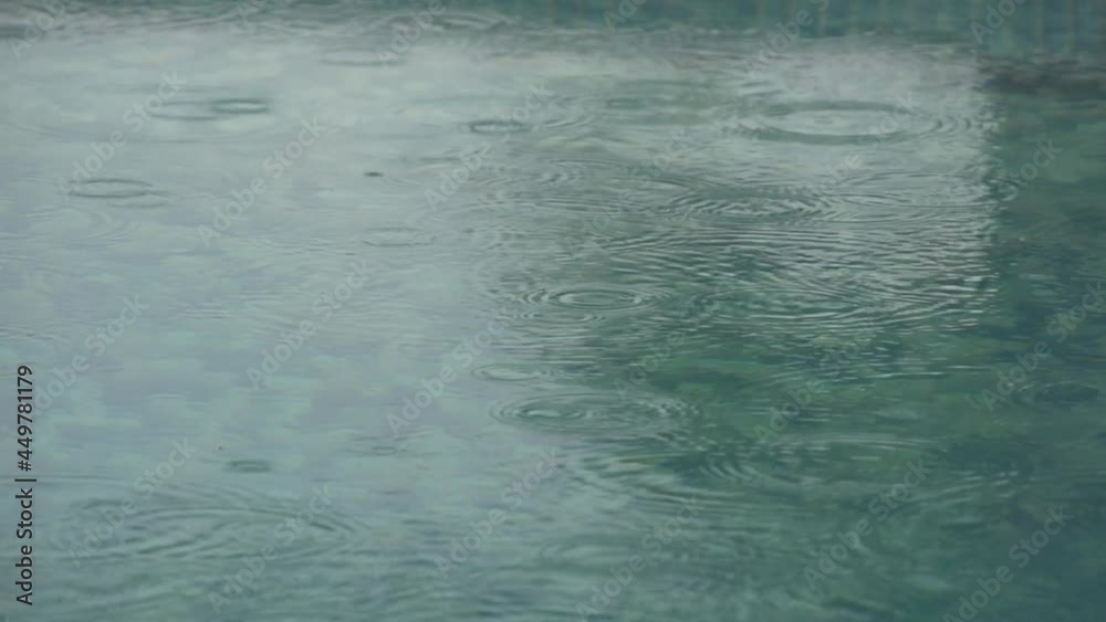 Super slow motion shot of raindrops falling on a quite water surface creating rings Super slow motion shot of raindrops falling on a quite water surface creating rings