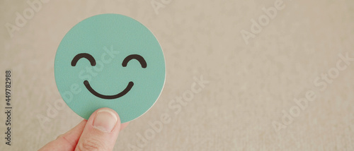 Hand holding green happy smile face paper cut, good feedback rating and positive customer review, experience, satisfaction survey ,mental health assessment, world mental health day concept photo