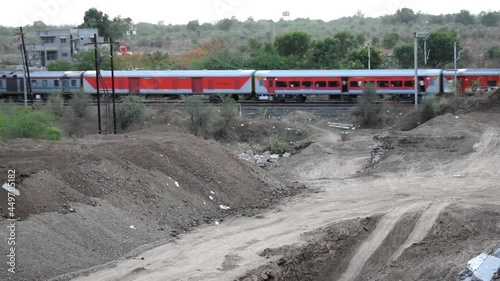 awesome close front engine view of Indian railway running on track goes to the horizon in the green landscape under blue sky with clouds. photo