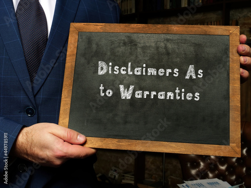 A handsome businessman showing a chalkboard with sign Disclaimers As to Warranties . Close-up shot. Soft focus. photo