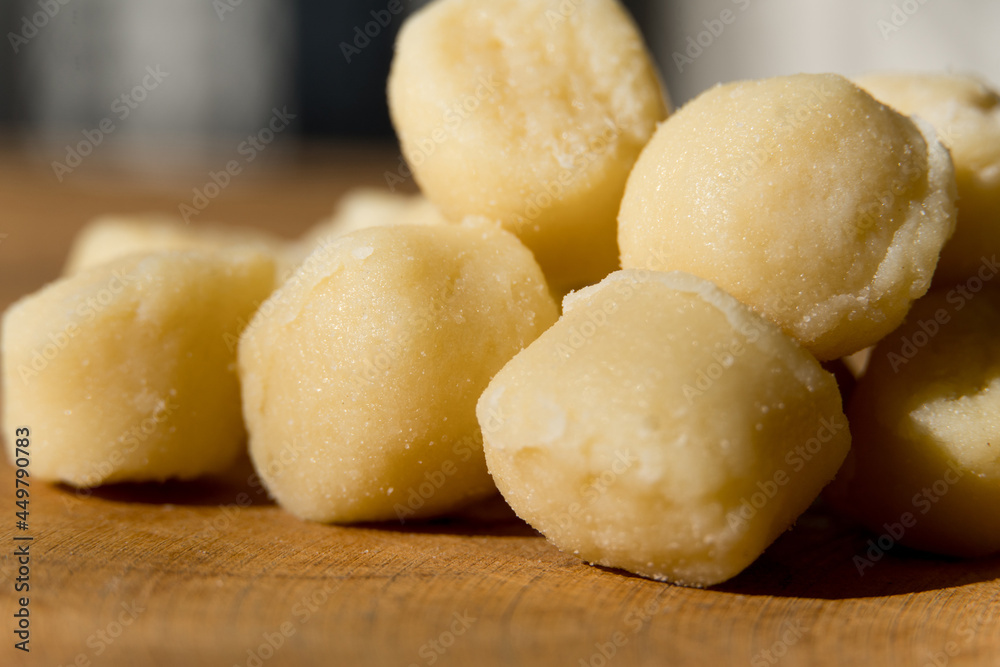Gnocchi pasta pre-cooked on a wooden board with grated cheese and basil. Macro close up. Selective focus. Gnocchi pasta pre-cooked on a wooden board with grated cheese and basil. Macro close up. Selective focus.