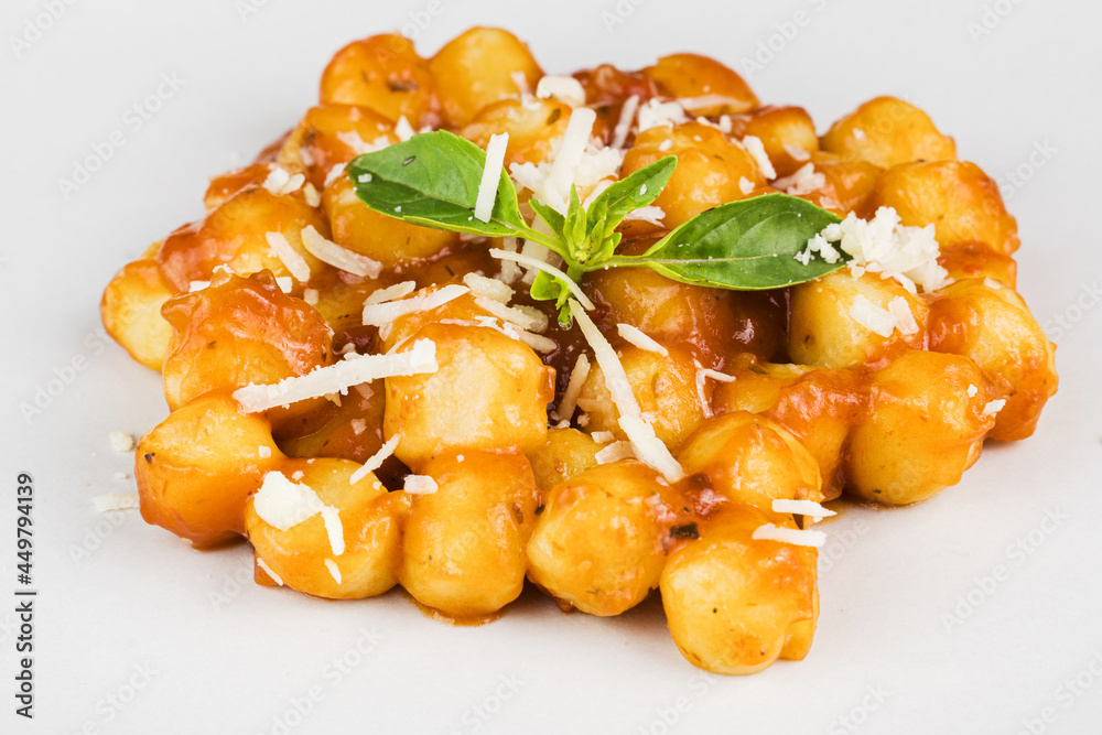 Gnocchi with juice sauce with grated cheese and basil served on the plate. Close-up. Selective focus. Gnocchi with juice sauce with grated cheese and basil served on the plate. Close-up. Selective focus.