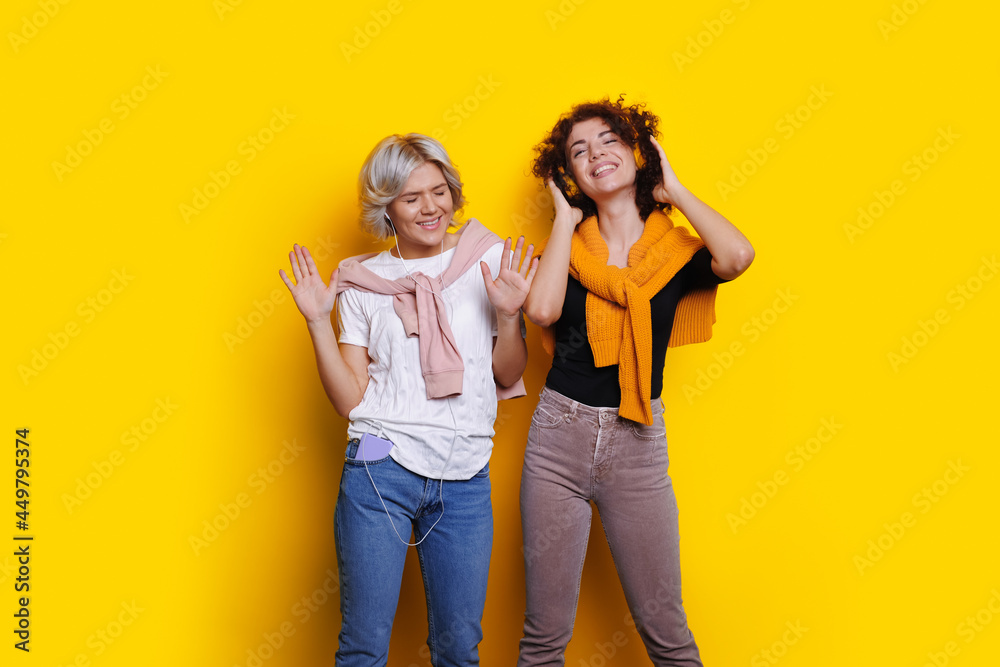 Fototapeta premium Yellow backdrop. Internet technology. Studio room. Dancing studio. Sisters listening to music