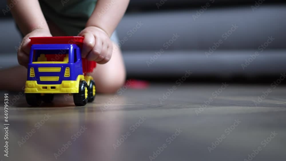 close-up low angle view of child kid hands playing with toy track car. plastic colorful track goes right to to the camera. transport vehicle insurance concept