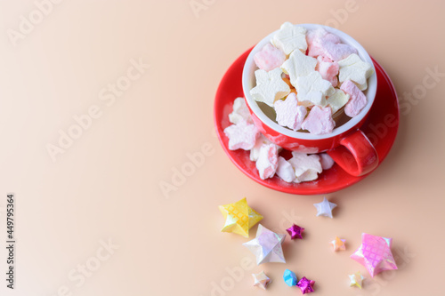 a cup of marhmallows against plain background. copy space. overexposed. soft focus. blurry background