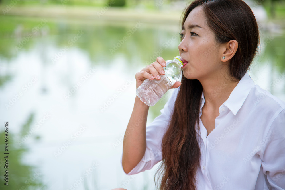Happiness Beautiful asian chinese women holding mineral water bottle. Young Woman Drinking Water from bottle in green garden Park. Asian female drinking water bottle healthy person happy and smiling Happiness Beautiful asian chinese women holding mineral water bottle. Young Woman Drinking Water from bottle in green garden Park. Asian female drinking water bottle healthy person happy and smiling