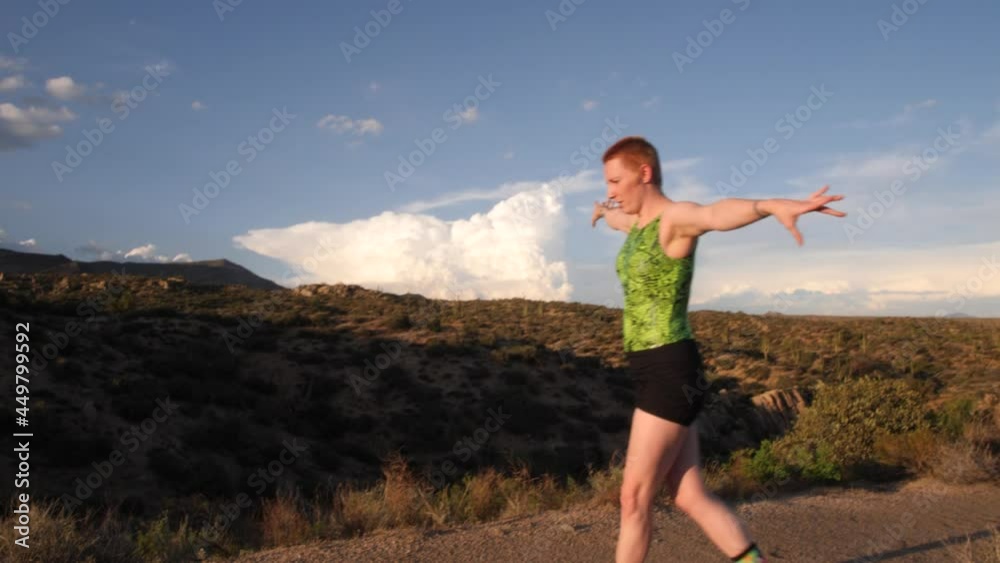 Acrobat leaps into the air stretching into a pose with clouds surrounding her in the desert. Acrobat leaps into the air stretching into a pose with clouds surrounding her in the desert.