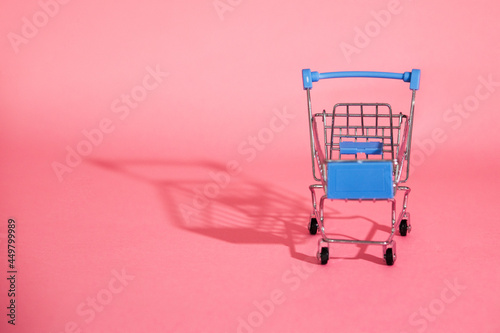 shopping cart on fresh pink background with copy space