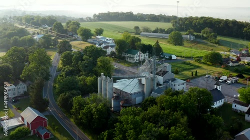 Rural small town in USA. Aerial orbit of feed mill and surrounding farm land in summer morning mist and light. photo