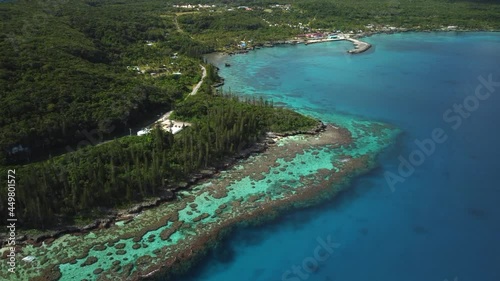 Aerial ascending shot revealing amazing coral bay beach and Tadine wharf, on Maré Island, New Caledonia photo