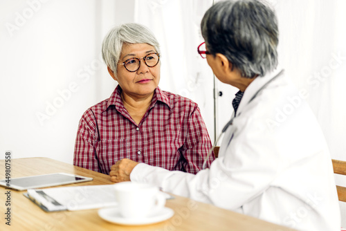 Senior woman doctor wearing uniform with stethoscope service help support discussing and consulting talk to sick woman patient about checkup result information with tablet computer in hospital