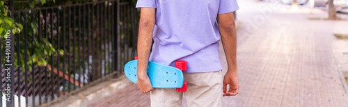 Young caucasian man in a park with a skate in back position