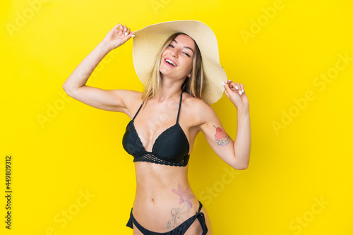 Young Romanian woman isolated on yellow background happy in swimsuit in summer holidays