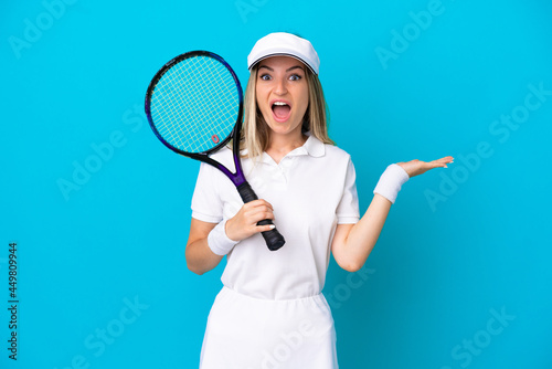 Young tennis player Romanian woman isolated on blue background with shocked facial expression © luismolinero