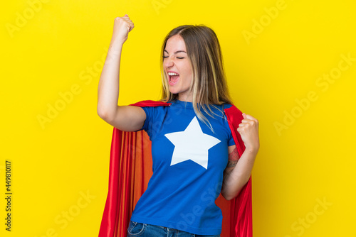Super Hero Romanian woman isolated on yellow background celebrating a victory