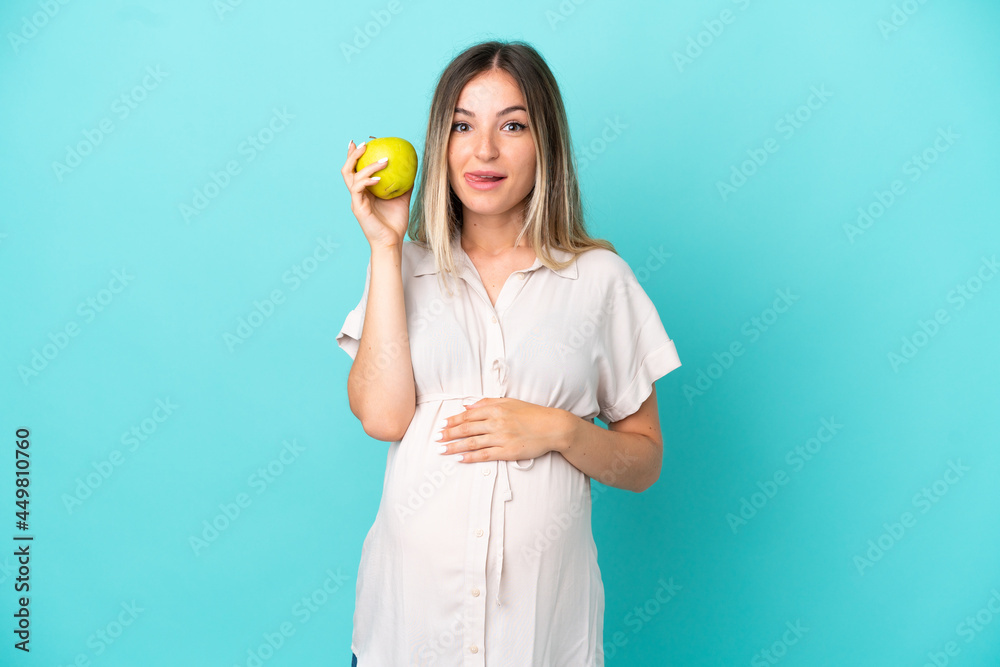 Young Romanian woman isolated on blue background pregnant and holding an apple Young Romanian woman isolated on blue background pregnant and holding an apple