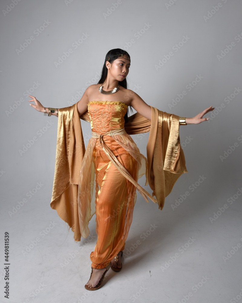 Full length portrait of pretty young asian woman wearing golden Arabian ...
