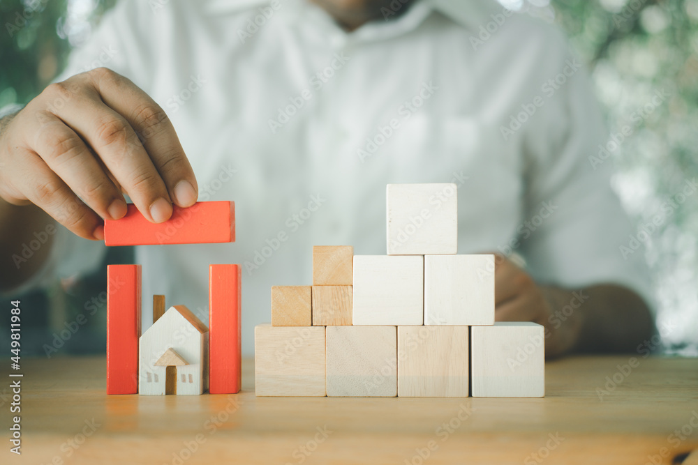 Businessman hand protects home with red block roof. Businessman hand protects home with red block roof.