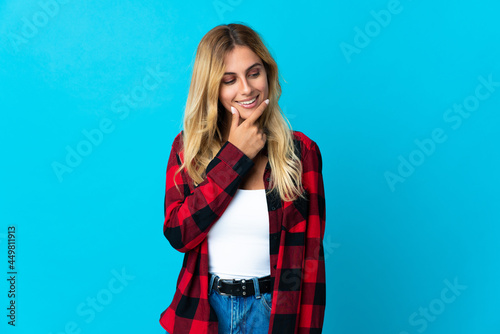 Young blonde Uruguayan woman over isolated background looking to the side and smiling