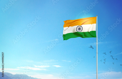 Huge Indian flag hoisted against blue sky with flying pigeons. India celebrates its Republic day on 26th of January.