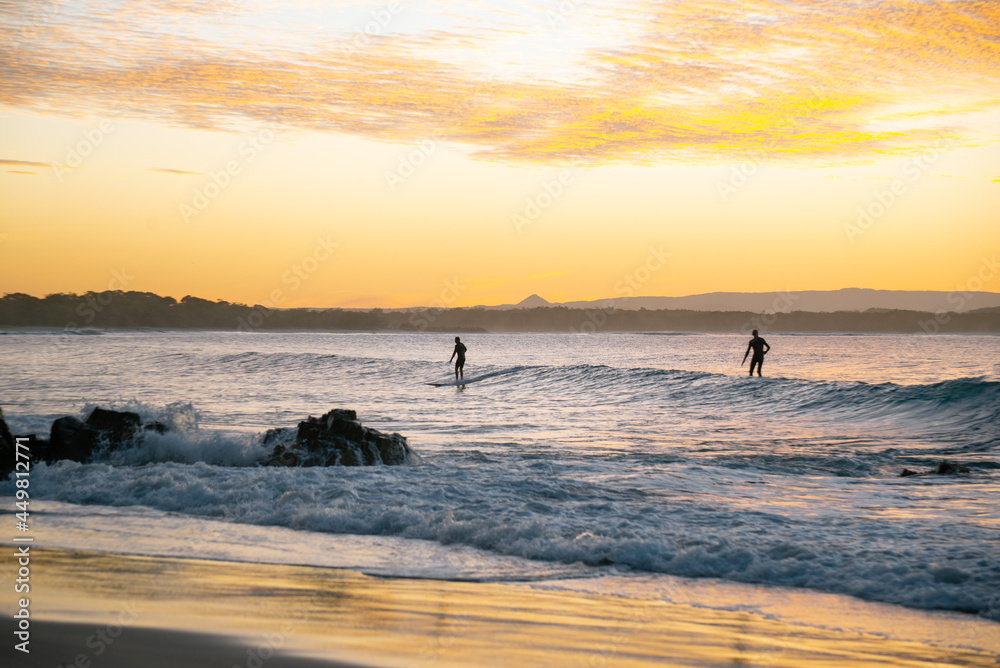 Silhouette of Surfers Ridding a Wave at Sunset Time in Noosa,Queensland,Australia.Lifestyle concept